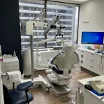 Dental chair, equipment, and a monitor in an examination room.